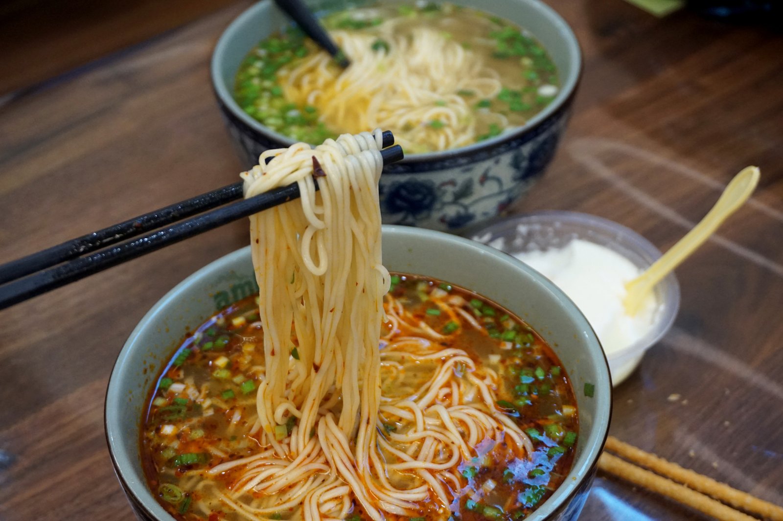 Fresh noodles lifted from a colorful bowl of Lanzhou-style beef noodles.