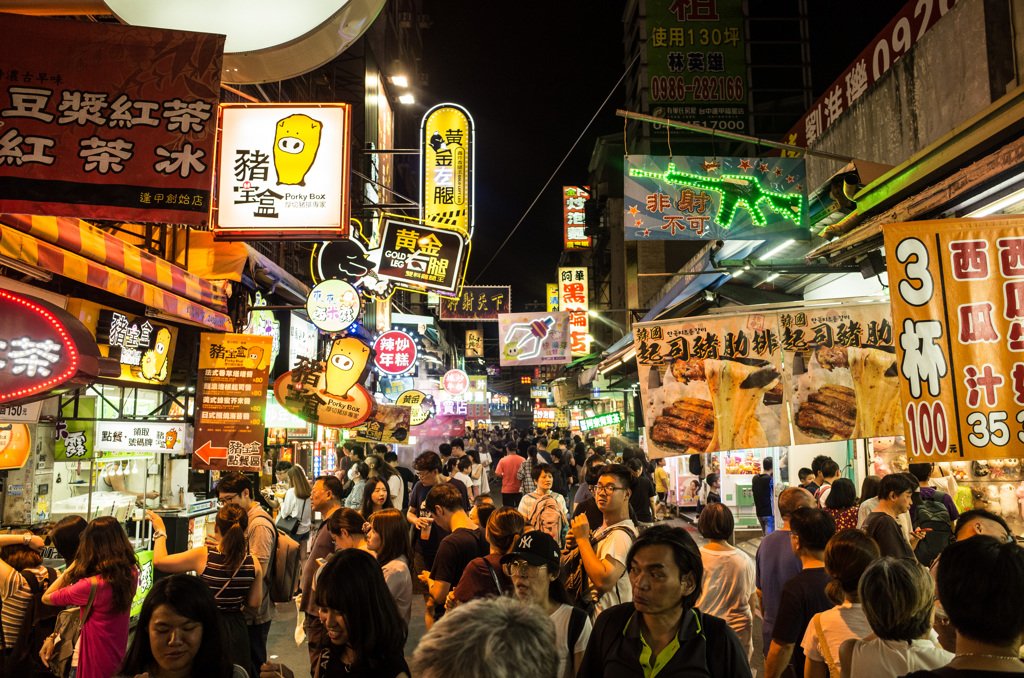 Visitors browse brightly lit food stalls at a lively night market in Taiwan.