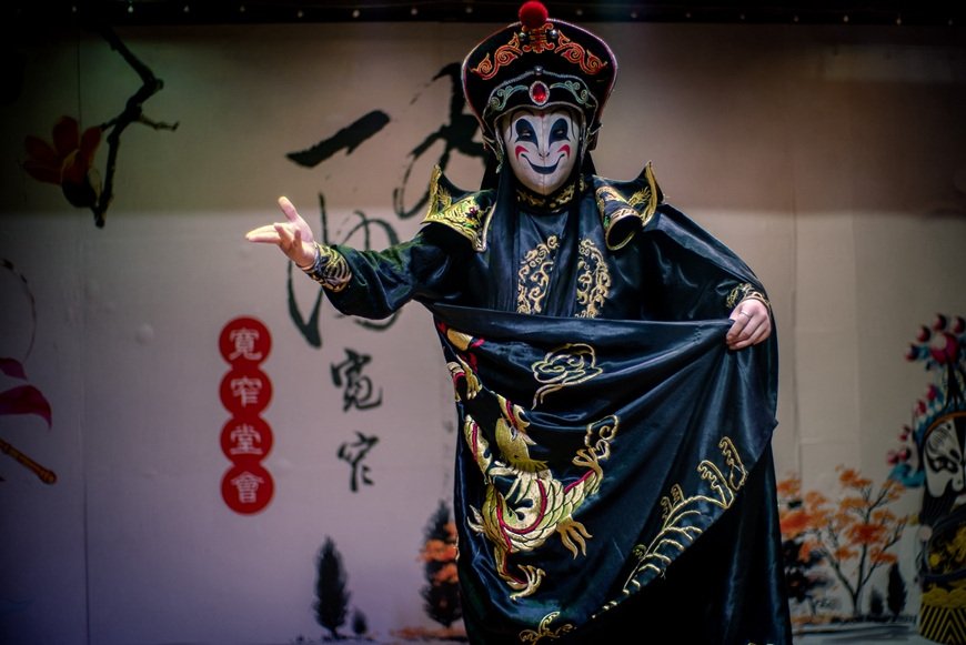 A Sichuan opera face-changing performer in an embroidered robe and ornate headdress.