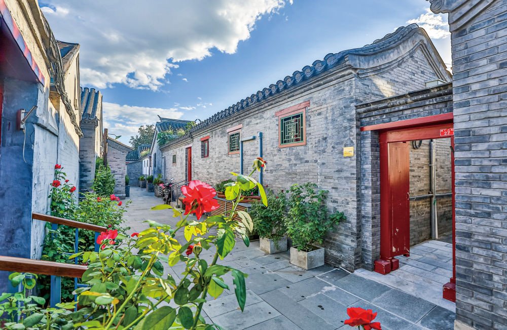 Flowers and red doorways brighten a clean lane in Beijing’s Caochang hutongs.