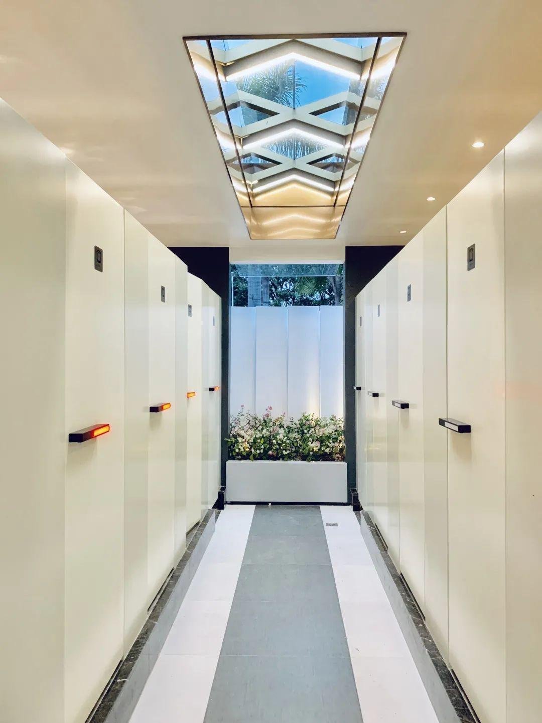 A bright modern public restroom corridor in Shenzhen, with skylights and clean cubicles.