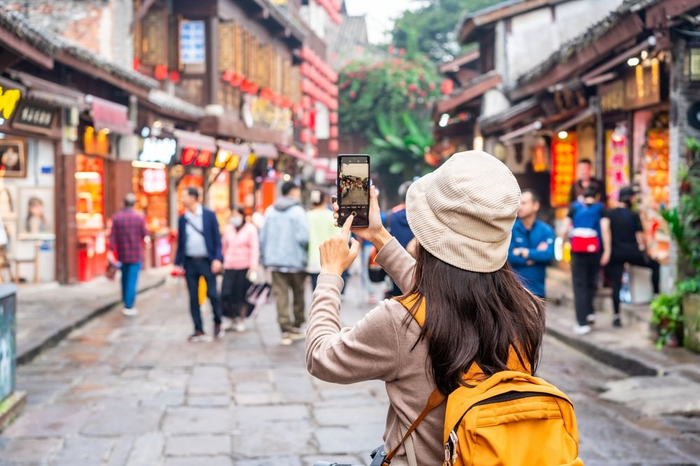 A traveler pauses to photograph a Chinese market street.