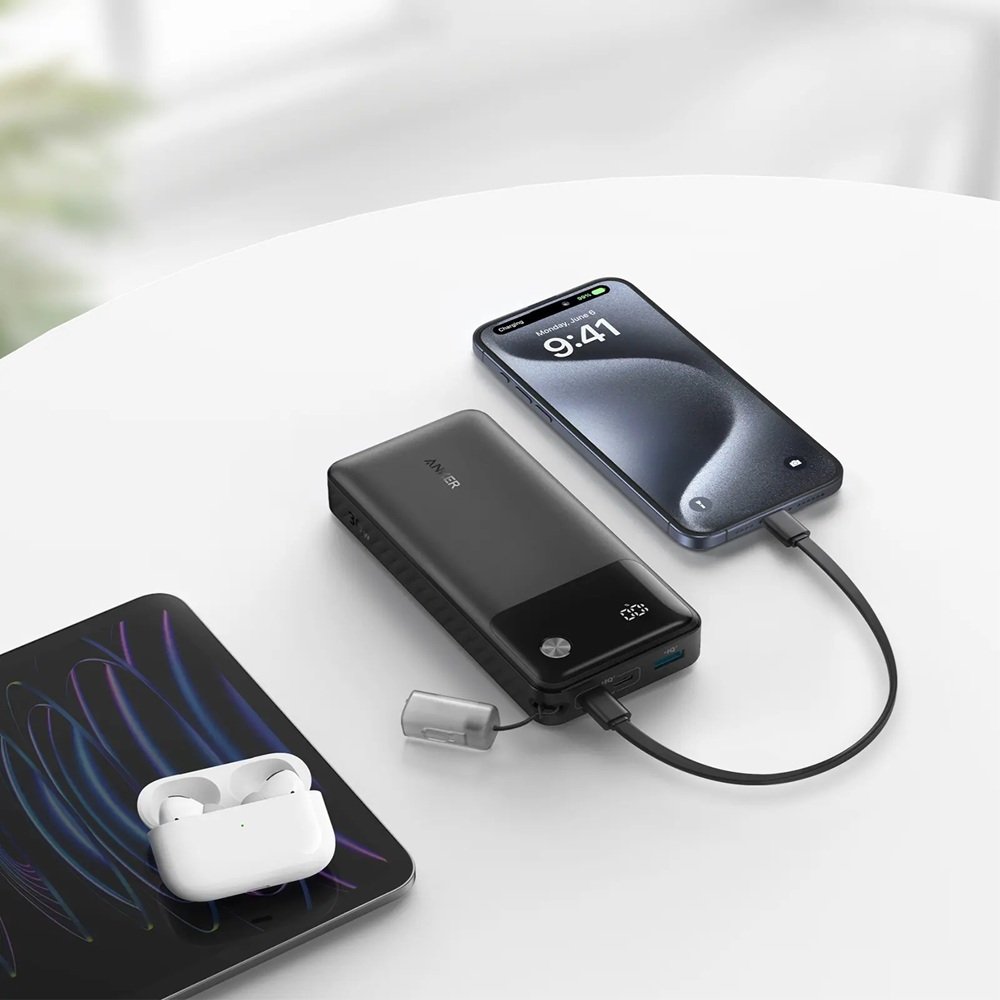 A portable power bank connected to a smartphone on a clean white desk