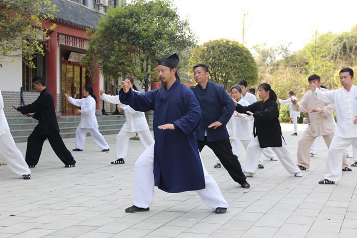 An instructor leads coordinated tai chi practice in the courtyard of Wudang Shixing Tai Chi Academy